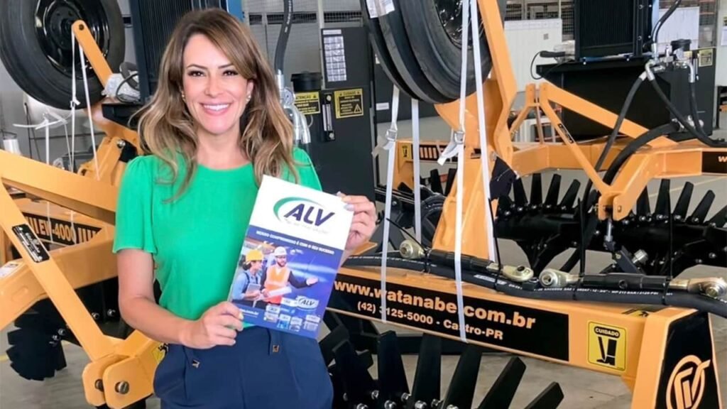Paola Crozetta, Representante Comercial, segura folder da ALV Tintas em frente à máquina agrícola escrito "Watanabe".